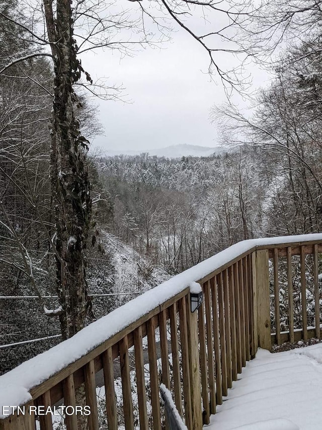 snow covered deck with a forest view