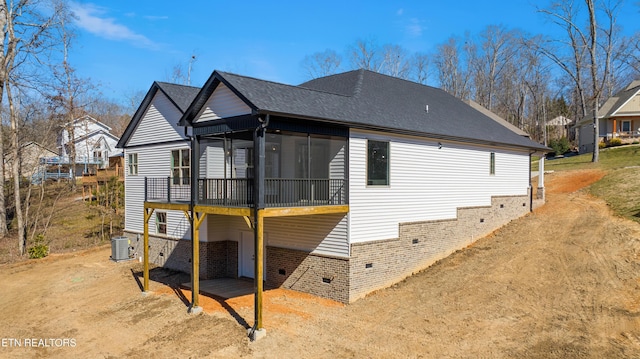 view of property exterior with a deck, central AC, roof with shingles, a sunroom, and brick siding