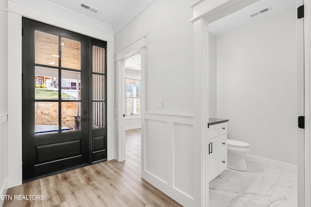 entrance foyer with baseboards, visible vents, marble finish floor, and ornamental molding