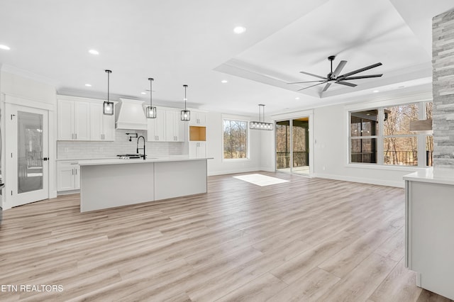 kitchen featuring light countertops, open floor plan, premium range hood, and backsplash