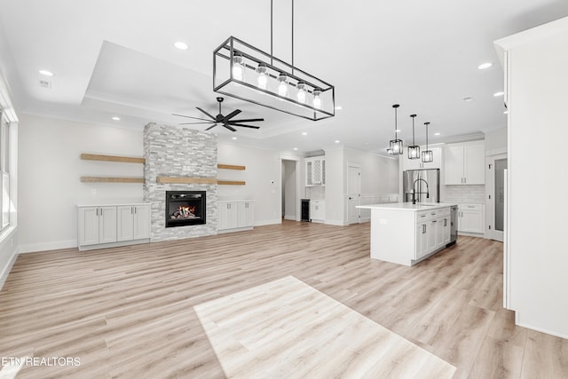 kitchen with ornamental molding, a ceiling fan, stainless steel fridge, a fireplace, and light countertops