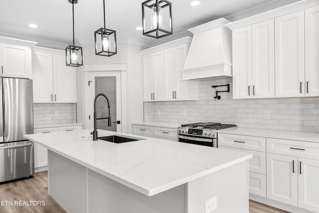 kitchen featuring a center island with sink, light wood-style flooring, a sink, stainless steel appliances, and custom exhaust hood