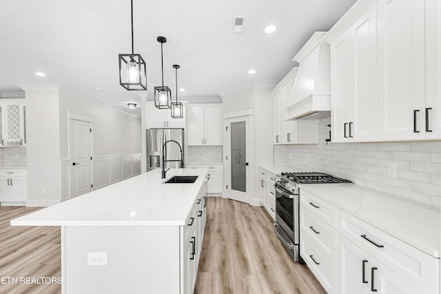 kitchen with crown molding, premium range hood, appliances with stainless steel finishes, white cabinets, and a sink