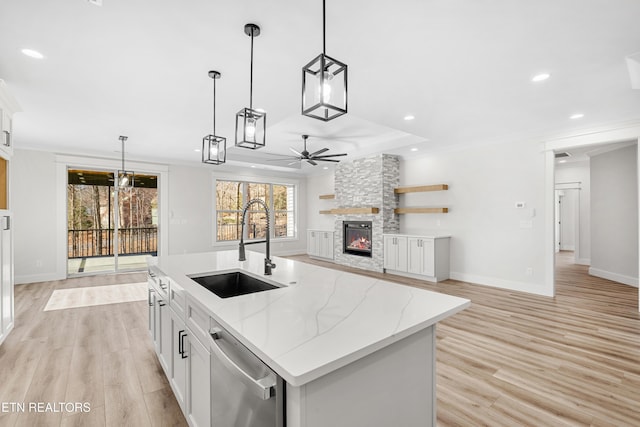 kitchen featuring a sink, stainless steel dishwasher, a fireplace, and crown molding