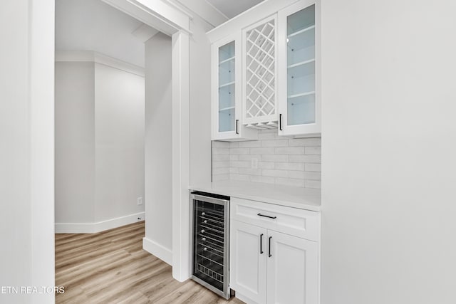 bar with light wood finished floors, tasteful backsplash, baseboards, wine cooler, and a dry bar