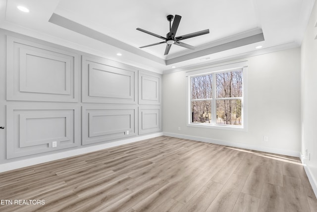 unfurnished bedroom with light wood finished floors, baseboards, crown molding, and a tray ceiling