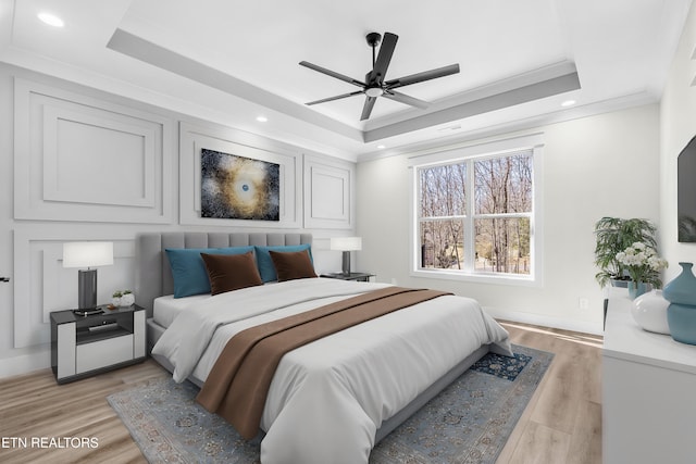 bedroom featuring recessed lighting, a raised ceiling, light wood-style flooring, and ornamental molding