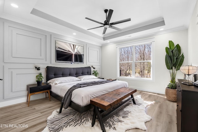 bedroom featuring baseboards, light wood-type flooring, a tray ceiling, ornamental molding, and recessed lighting