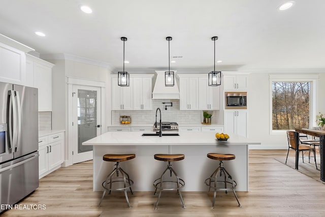 kitchen with a kitchen bar, a sink, appliances with stainless steel finishes, white cabinets, and custom exhaust hood