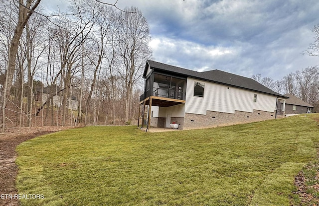 back of house featuring crawl space, a lawn, and a sunroom