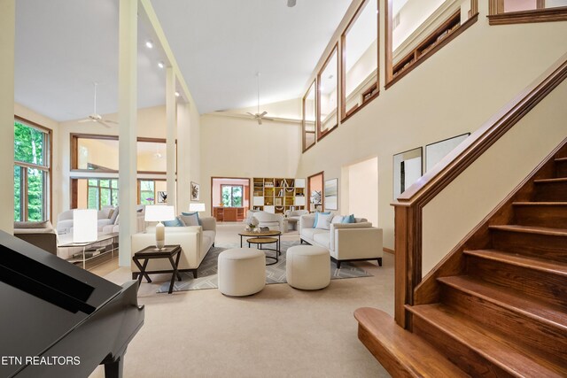 living room featuring plenty of natural light, ceiling fan, carpet floors, and stairway