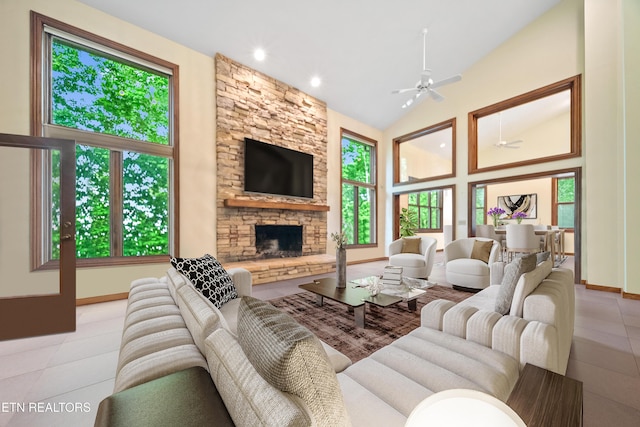 living room featuring ceiling fan, a fireplace, high vaulted ceiling, baseboards, and tile patterned floors