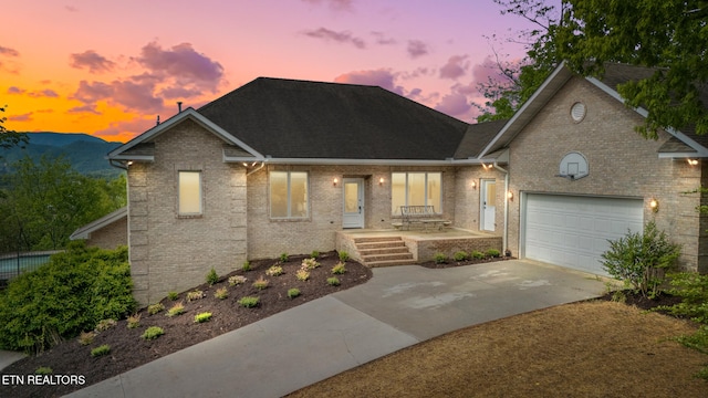 view of front of home with driveway, roof with shingles, brick siding, a mountain view, and an attached garage