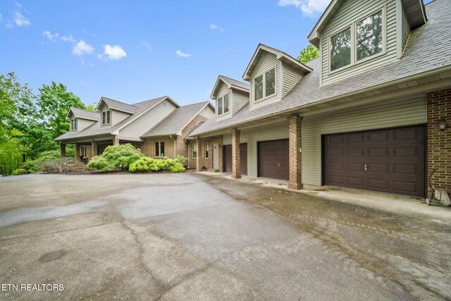 view of property exterior featuring brick siding, driveway, and a garage