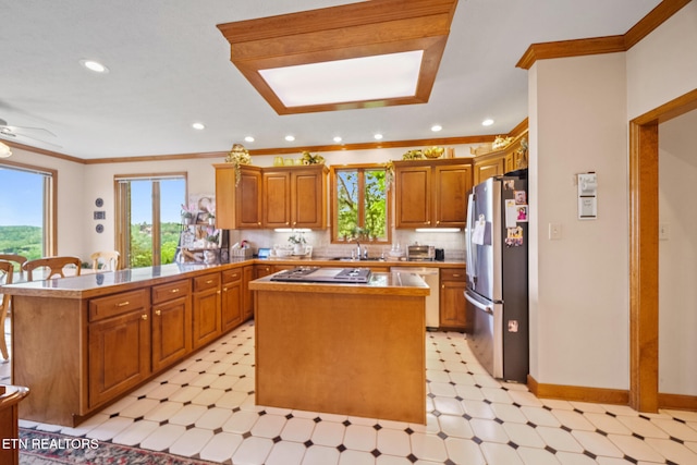 kitchen with appliances with stainless steel finishes, a sink, a peninsula, light floors, and a kitchen island