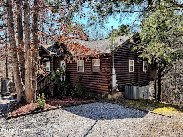 view of side of home with a shingled roof, cooling unit, and log siding