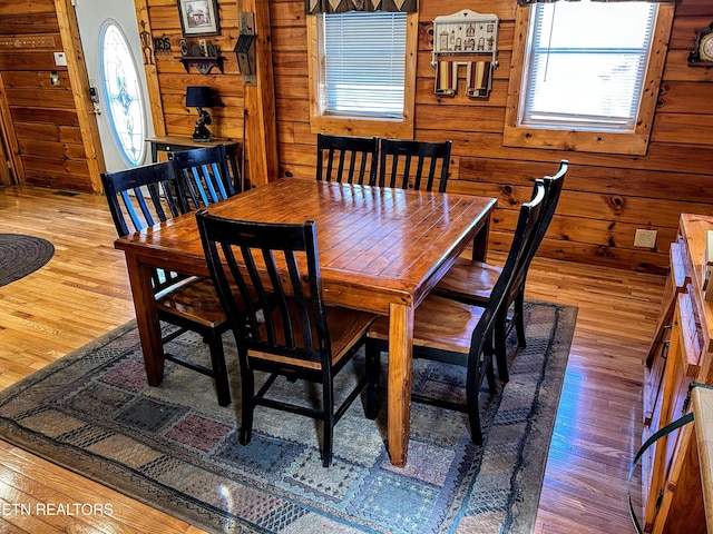 dining space with wood-type flooring and wooden walls