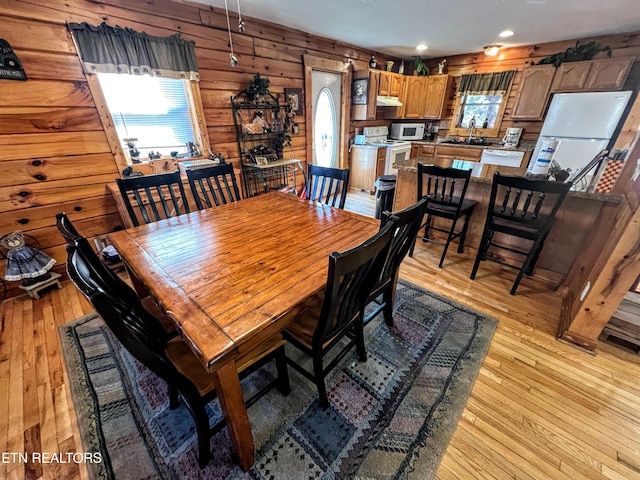 dining area featuring light wood finished floors, wooden walls, and recessed lighting