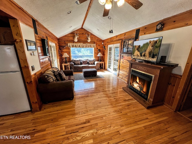 living area featuring vaulted ceiling, wood walls, wood-type flooring, and a textured ceiling