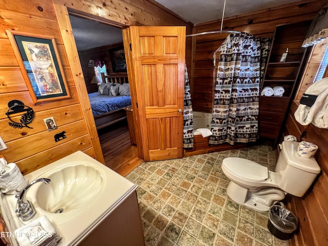 bathroom with wooden walls, toilet, shower / tub combo with curtain, vaulted ceiling, and vanity