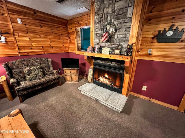 carpeted living room featuring a textured ceiling and a stone fireplace