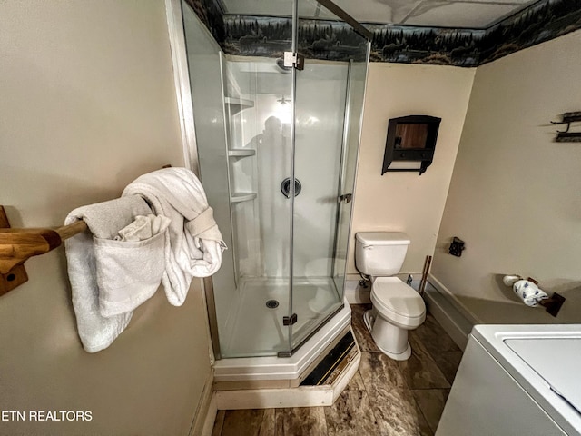 bathroom with toilet, a stall shower, and washer / clothes dryer