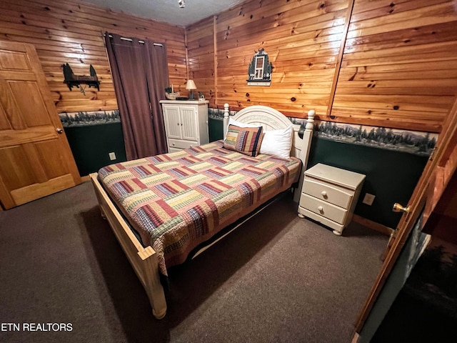 bedroom featuring dark colored carpet and wood walls