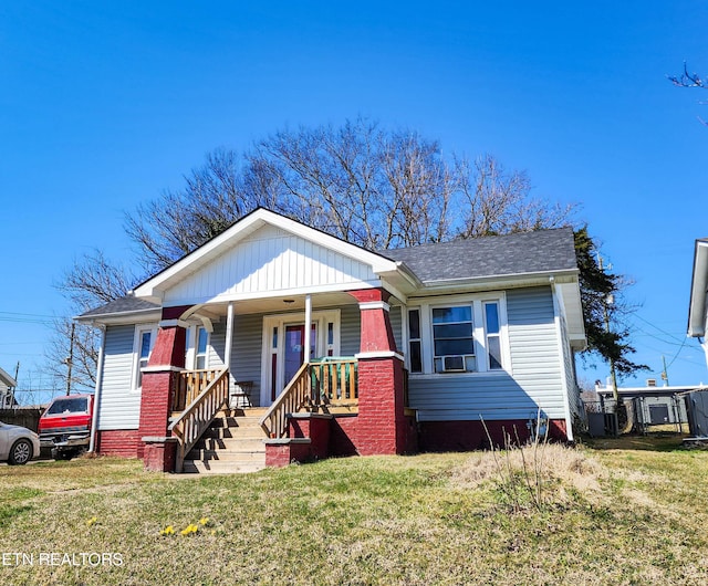 bungalow with covered porch and a front lawn