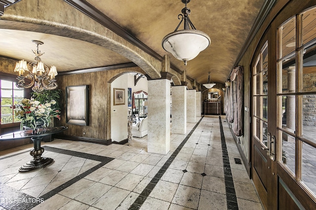 interior space with arched walkways, crown molding, a notable chandelier, and baseboards