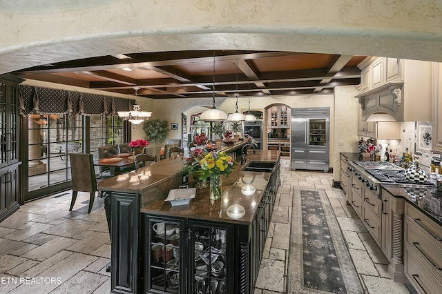 kitchen featuring appliances with stainless steel finishes, a spacious island, a sink, and stone tile floors