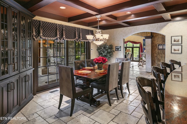 dining room featuring arched walkways, coffered ceiling, beamed ceiling, and stone tile floors