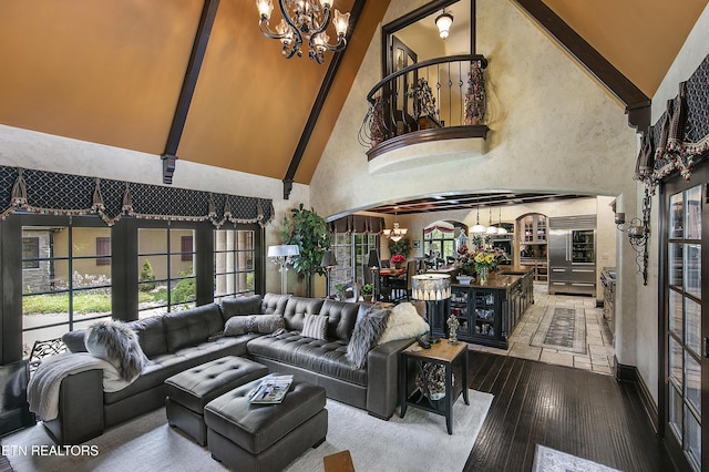 living area featuring arched walkways, hardwood / wood-style floors, a towering ceiling, and an inviting chandelier