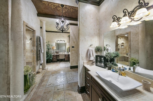 bathroom with a chandelier, a stall shower, stone tile flooring, and vanity