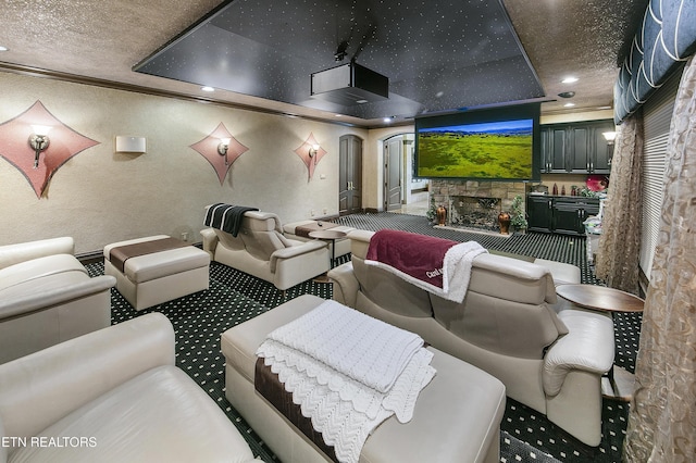 carpeted home theater featuring recessed lighting, a textured ceiling, crown molding, and a stone fireplace