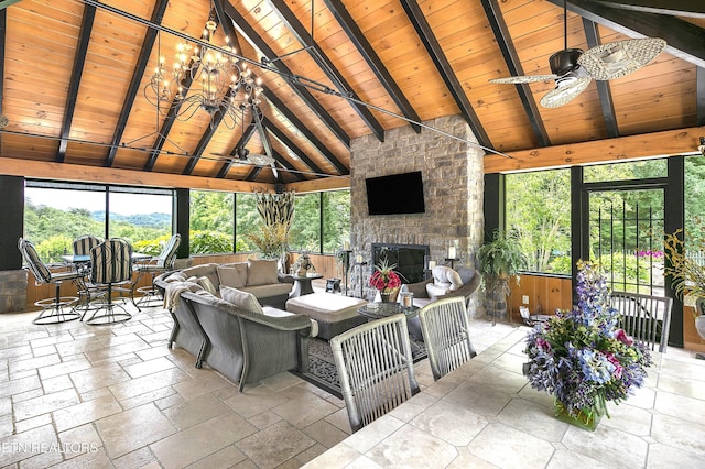 living room featuring a fireplace, stone tile flooring, a ceiling fan, wood ceiling, and beamed ceiling