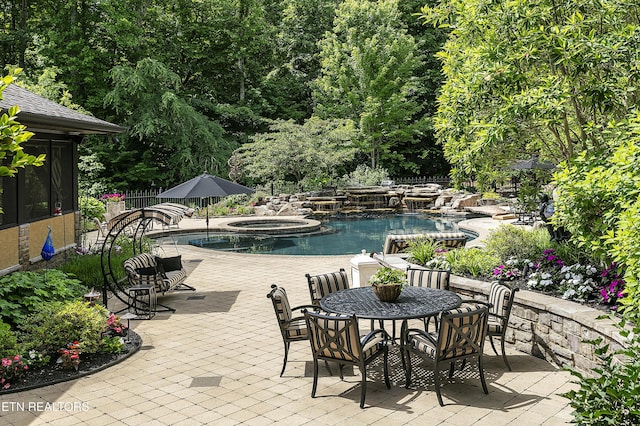 view of swimming pool with a patio, fence, and a pool with connected hot tub