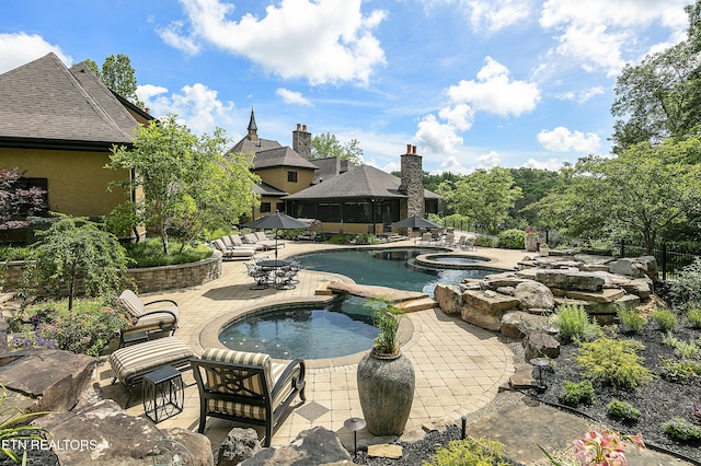 pool featuring an in ground hot tub and a patio