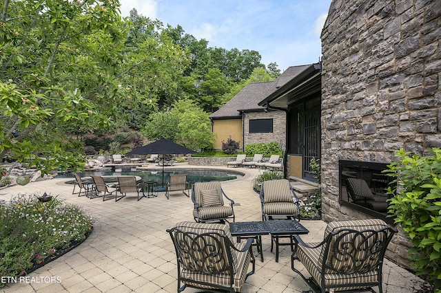 view of patio / terrace with an outdoor stone fireplace and an outdoor pool