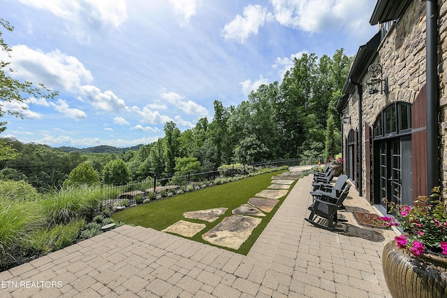 view of patio / terrace featuring fence and a wooded view