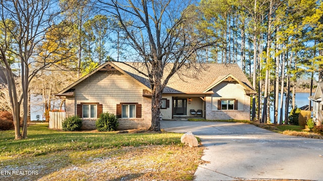 view of front facade with a front yard, brick siding, and driveway