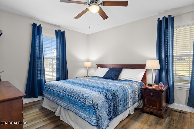 bedroom featuring a ceiling fan, visible vents, baseboards, and wood finished floors