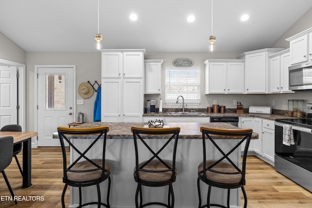 kitchen with stainless steel appliances, a breakfast bar, a sink, and white cabinetry