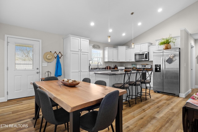 dining room with high vaulted ceiling, recessed lighting, light wood-style flooring, and baseboards