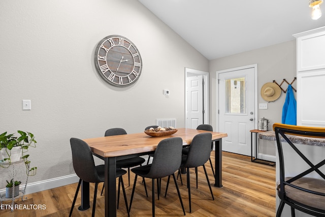 dining area with lofted ceiling, light wood-style flooring, visible vents, and baseboards