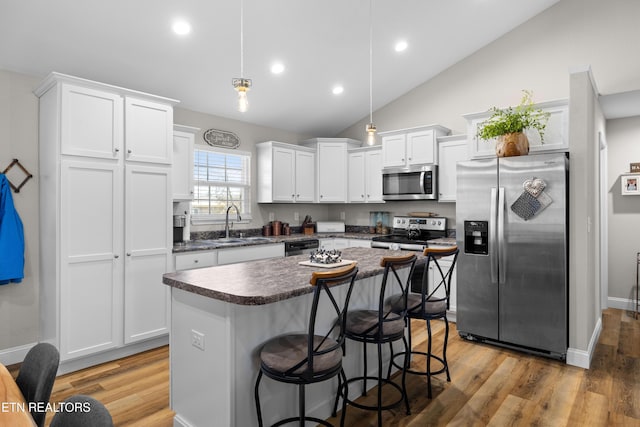 kitchen featuring stainless steel appliances, light wood-type flooring, dark countertops, and white cabinets