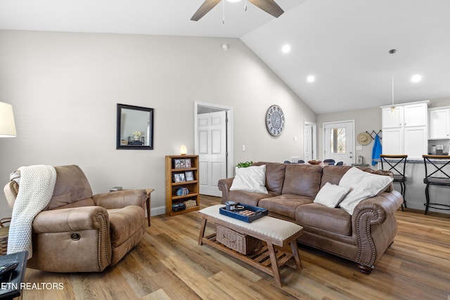 living room featuring high vaulted ceiling, light wood-type flooring, ceiling fan, and recessed lighting