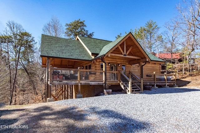 view of front facade featuring a shingled roof and log siding