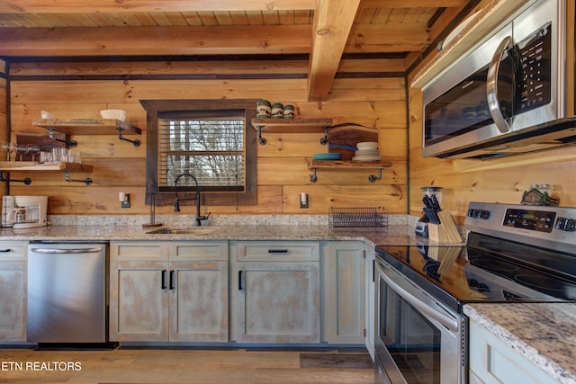 kitchen featuring beamed ceiling, stainless steel appliances, wood walls, open shelves, and a sink