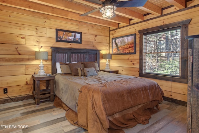 bedroom featuring beamed ceiling, wood finished floors, and wooden walls