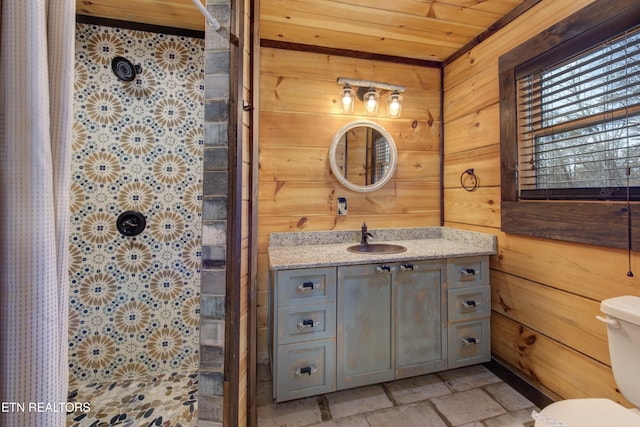 full bathroom with stone tile floors, toilet, wood walls, vanity, and a shower with curtain